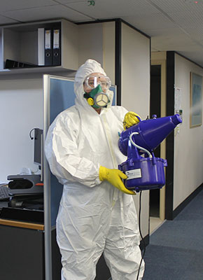 Covid-19 protection. Cleaner dressed in enclosed suit with fogger